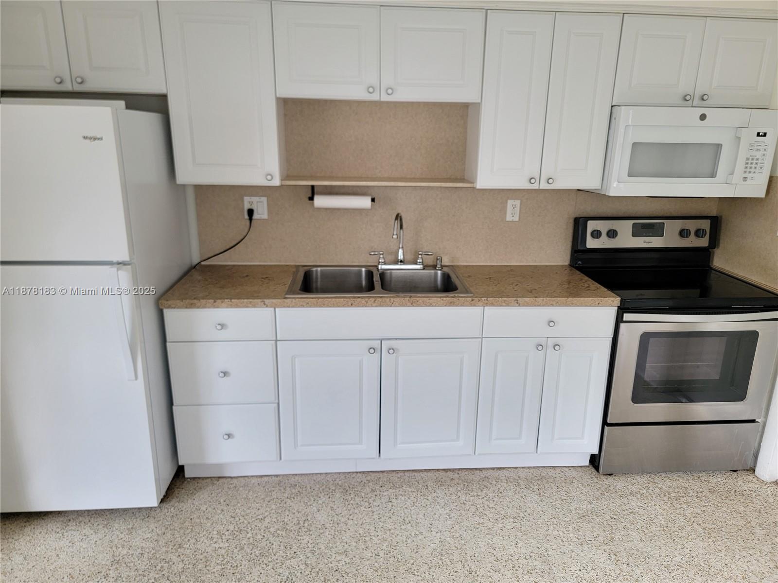 3375 Southwest 28th Street, Unit 3375 Miami, FL 33133 - Photo 5 of 20 a kitchen with granite countertop white cabinets and refrigerator