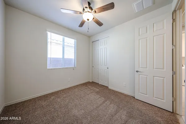 an empty room with windows and fan