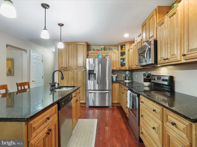 a kitchen with stainless steel appliances granite countertop a kitchen island hardwood floor and a sink