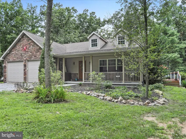 a view of a house with a yard plants and large tree