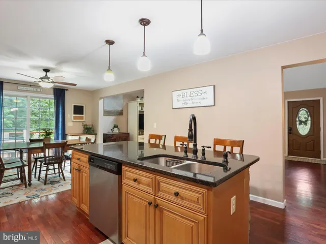 a kitchen with stainless steel appliances granite countertop a refrigerator a sink dishwasher a stove and a refrigerator with wooden floor