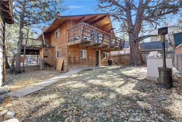 a view of a backyard with large trees and wooden fence
