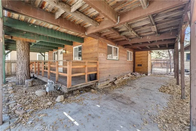 a view of a white house with a large tree and wooden fence