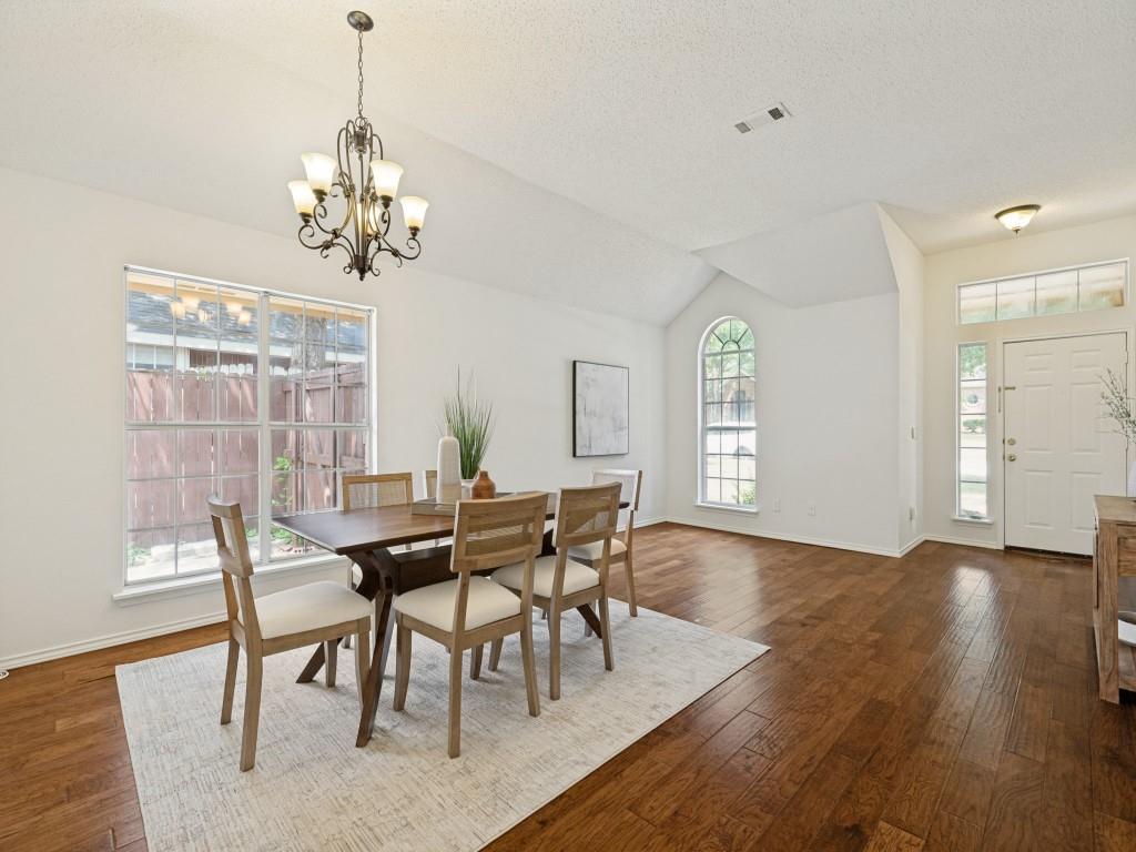 7641 King Arthur Road Frisco, TX 75035 - Photo 2 of 16 Vaulted ceiling with an ornate chandelier, multiple windows, wood-finish flooring, and white interior paint