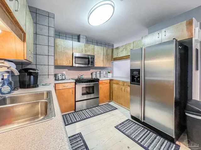 a kitchen with stainless steel appliances granite countertop a refrigerator a stove and a sink with granite countertops