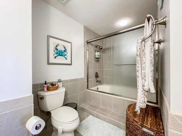 a white toilet sitting next to a bath tub and a shower