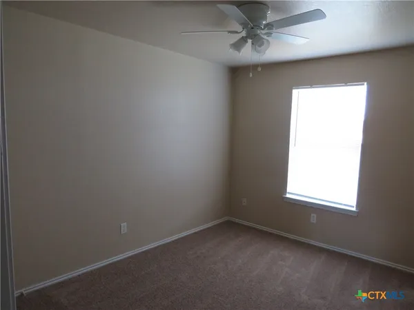 an empty room with a window and a fan