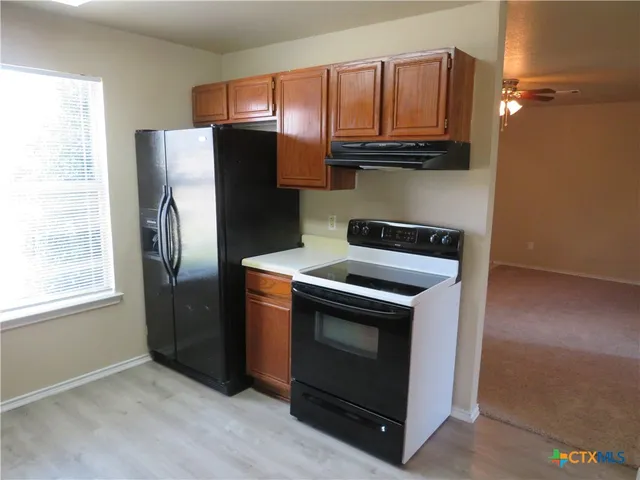 a kitchen with granite countertop a refrigerator stove and microwave