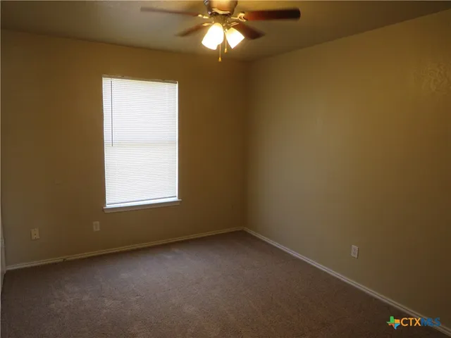 an empty room with a chandelier fan and windows
