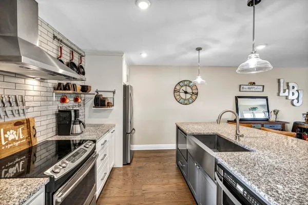 a kitchen with stainless steel appliances granite countertop a stove top oven a sink and a refrigerator