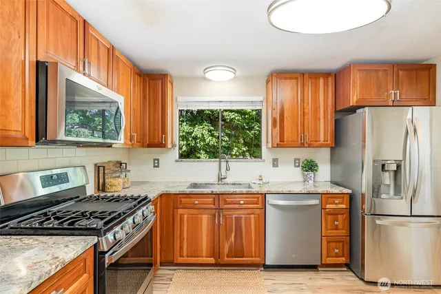 a kitchen with a refrigerator a stove a sink and a window