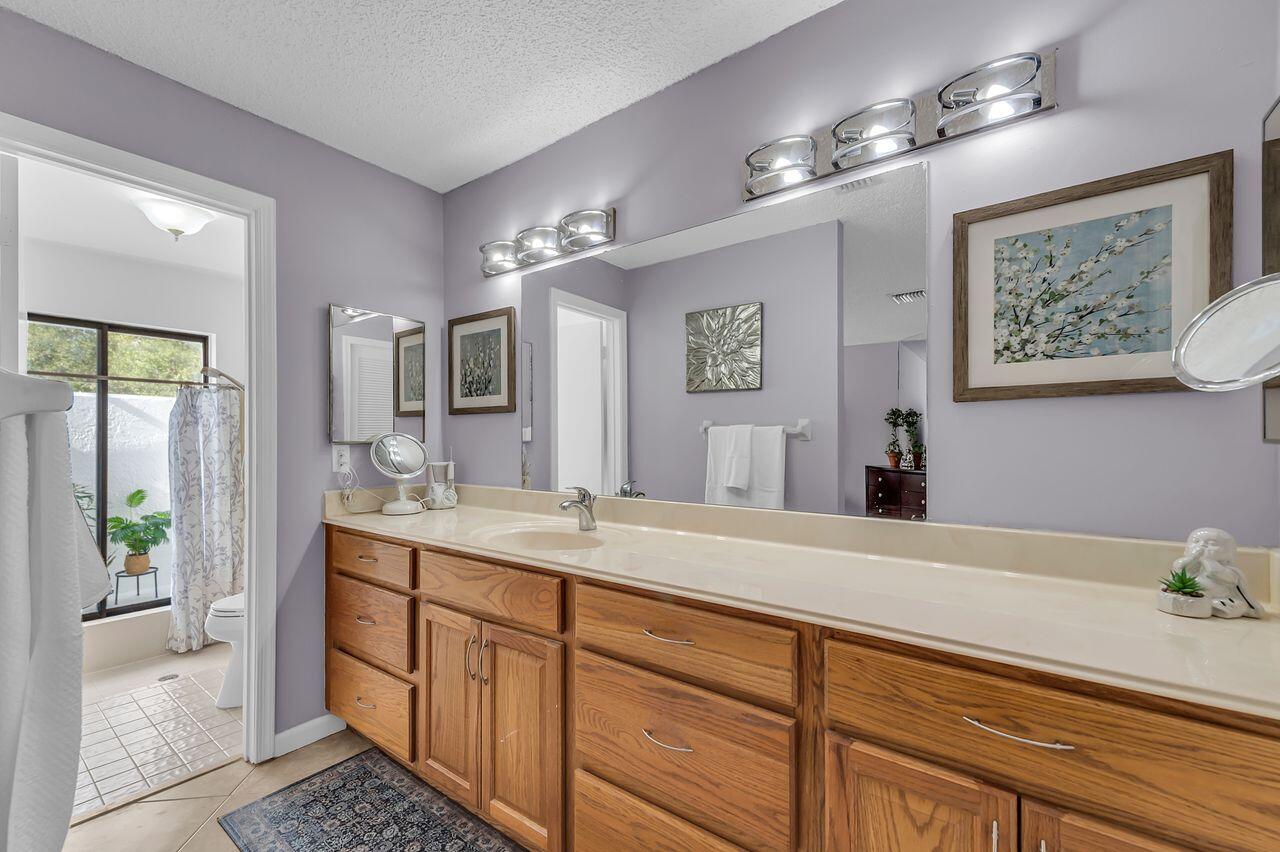 19699 Boca Greens Drive Boca Raton, FL 33498 - Photo 15 of 43 a spacious bathroom with a granite countertop sink a toilet a mirror and vanity