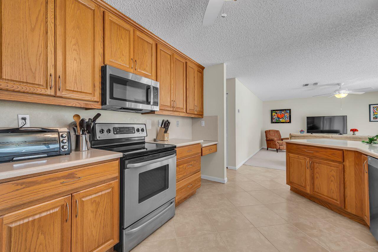 19699 Boca Greens Drive Boca Raton, FL 33498 - Photo 21 of 43 a kitchen with stainless steel appliances granite countertop a stove a sink dishwasher and a microwave oven with white cabinets