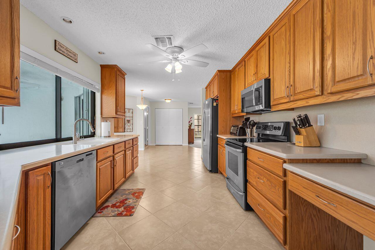 19699 Boca Greens Drive Boca Raton, FL 33498 - Photo 22 of 43 a kitchen with stainless steel appliances granite countertop a refrigerator a sink dishwasher and white cabinets with wooden floor