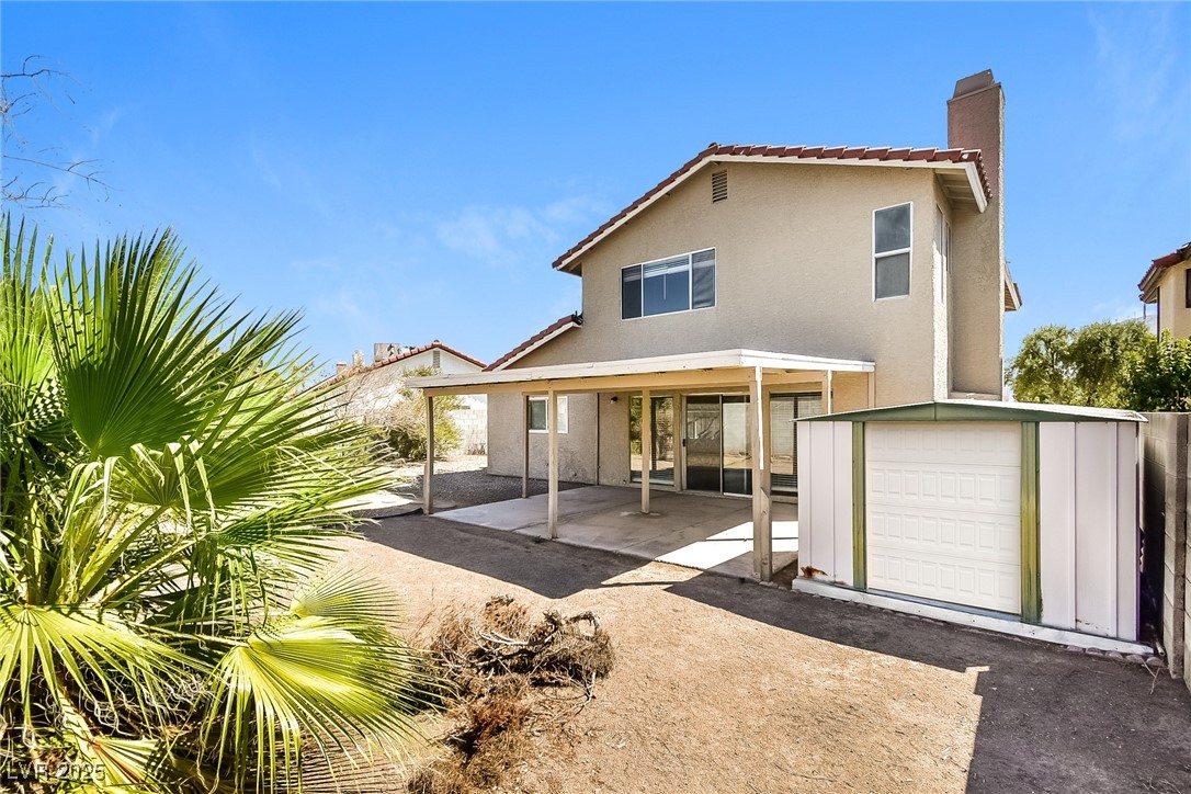 741 Round Table Drive Las Vegas, NV 89110 - Photo 19 of 22 Back of property with a patio area, a chimney, stucco siding, and a storage unit