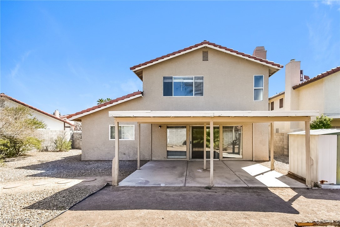 741 Round Table Drive Las Vegas, NV 89110 - Photo 20 of 22 Back of house with stucco siding, a patio area, a chimney, and a storage unit