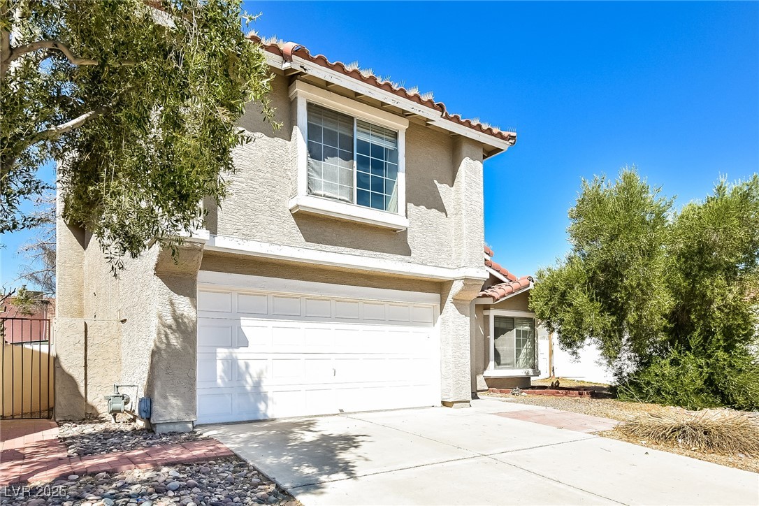 741 Round Table Drive Las Vegas, NV 89110 - Photo 4 of 22 Traditional-style home with a garage, a tiled roof, stucco siding, and driveway