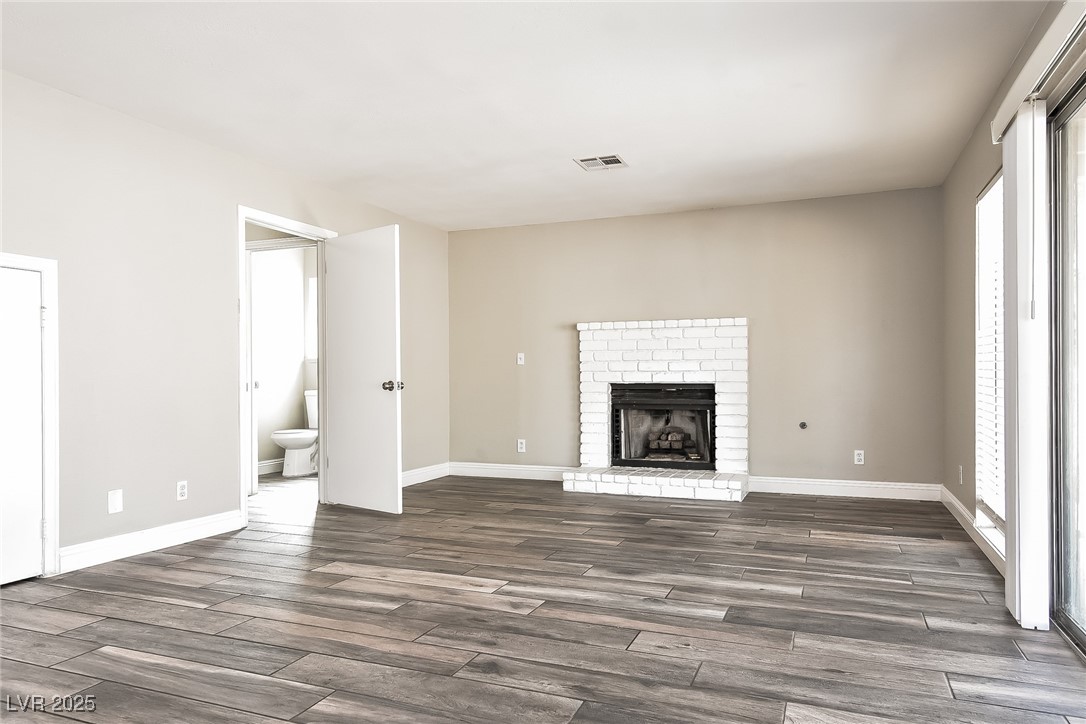 741 Round Table Drive Las Vegas, NV 89110 - Photo 8 of 22 Unfurnished living room with a brick fireplace and dark wood finished floors