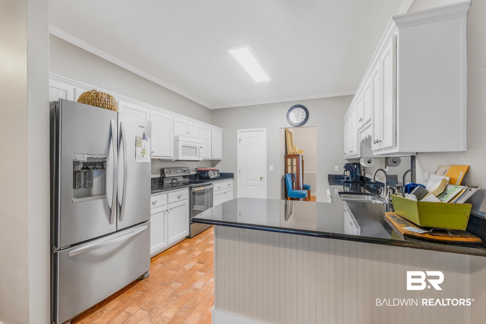 10603 Old Stage Road Stockton, AL 36579 - Photo 14 of 34 Kitchen with stainless steel appliances, white cabinets, ornamental molding, a peninsula, and light wood finished floors
