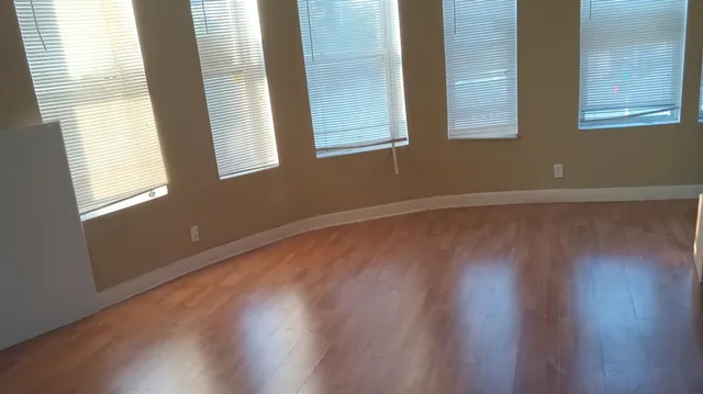 a view of an empty room with wooden floor and a window