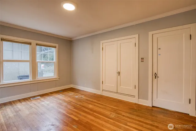 a view of an empty room with wooden floor and a window