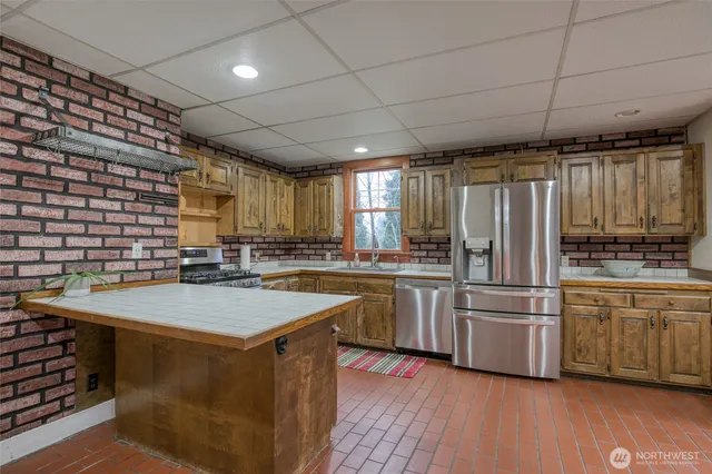 a kitchen with stainless steel appliances granite countertop a stove a sink dishwasher and a refrigerator with wooden floor