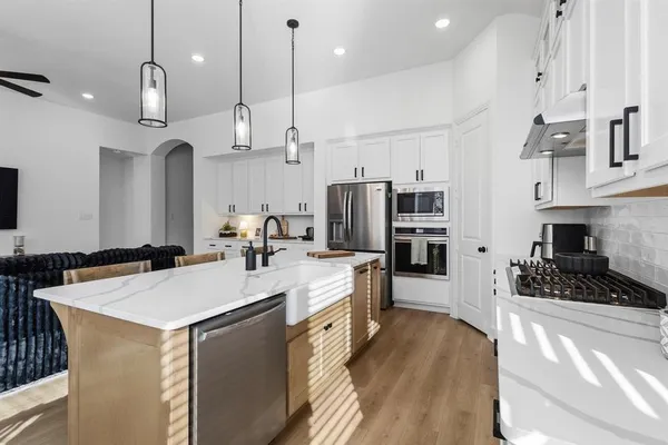 a kitchen with stainless steel appliances a stove a sink a refrigerator a center island a stove and a cabinets