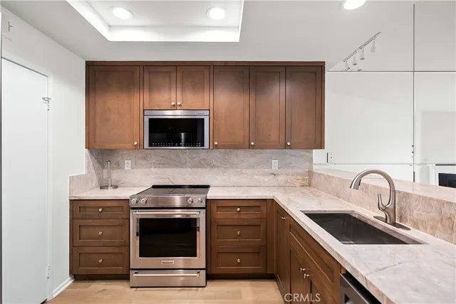 a kitchen with stainless steel appliances granite countertop a sink and cabinets with wooden floor