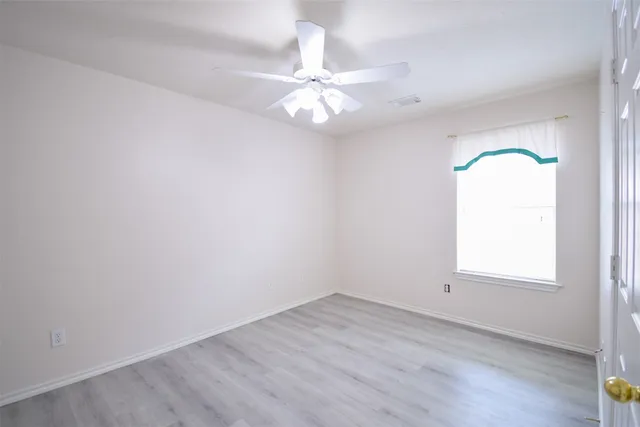 an empty room with a window and a chandelier fan