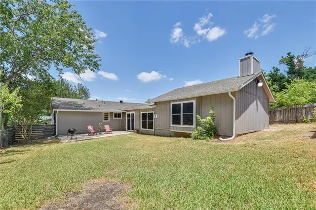 a front view of house with yard and trees in the background