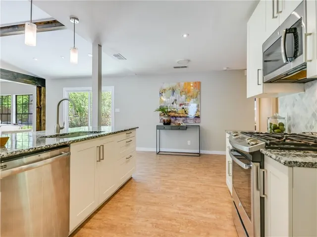 a kitchen with stainless steel appliances granite countertop a stove a sink and a microwave