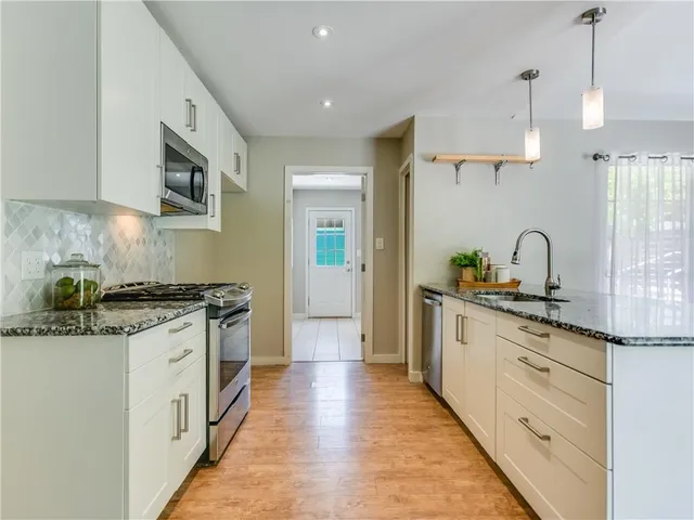a kitchen with stainless steel appliances granite countertop a stove a sink and a refrigerator
