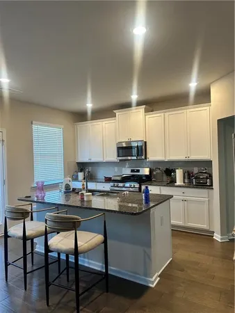 a kitchen with stainless steel appliances granite countertop a stove top oven a sink dishwasher a dining table and chairs with wooden floor