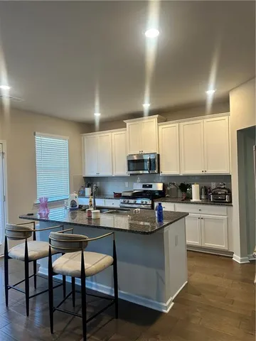 a kitchen with stainless steel appliances granite countertop a stove top oven a sink dishwasher a dining table and chairs with wooden floor