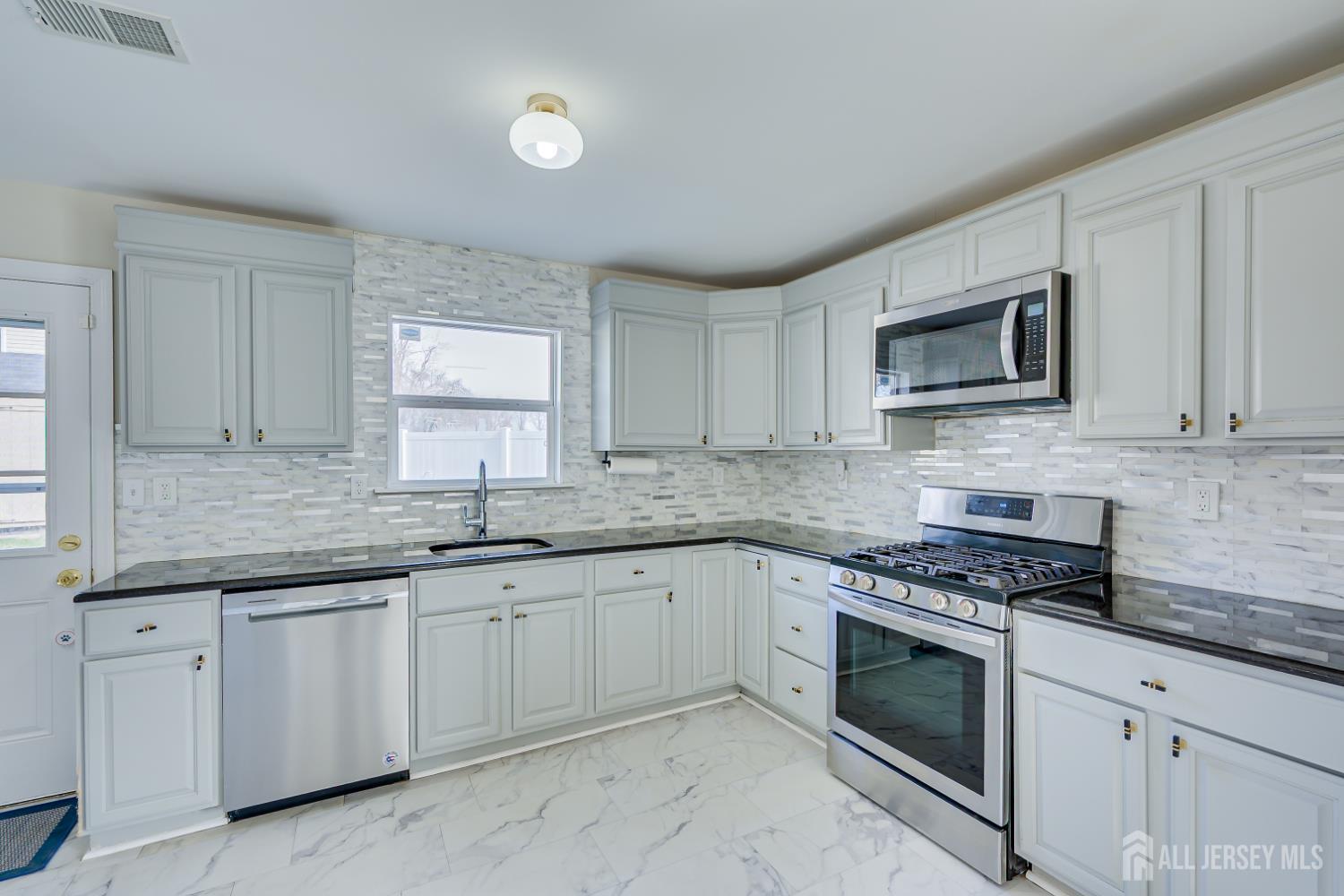 17 Idlewild Road Edison, NJ 08817 - Photo 16 of 36 a kitchen with granite countertop white cabinets sink and stainless steel appliances