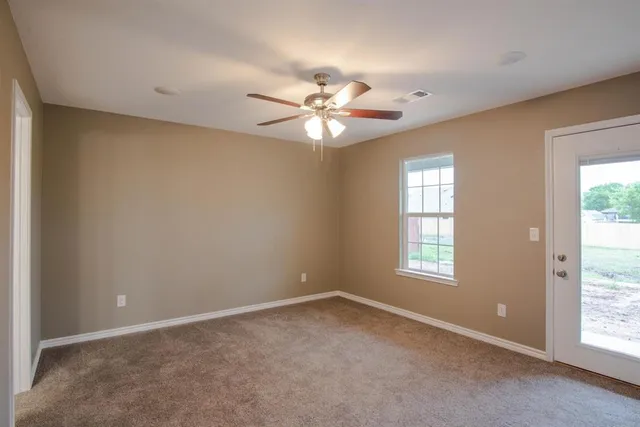 an empty room with windows and fan