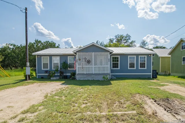 a view of a house with a yard and a large tree