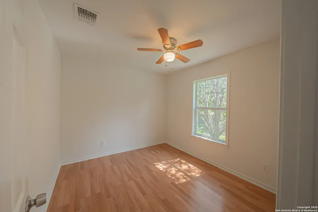 a view of an empty room and window with a fan