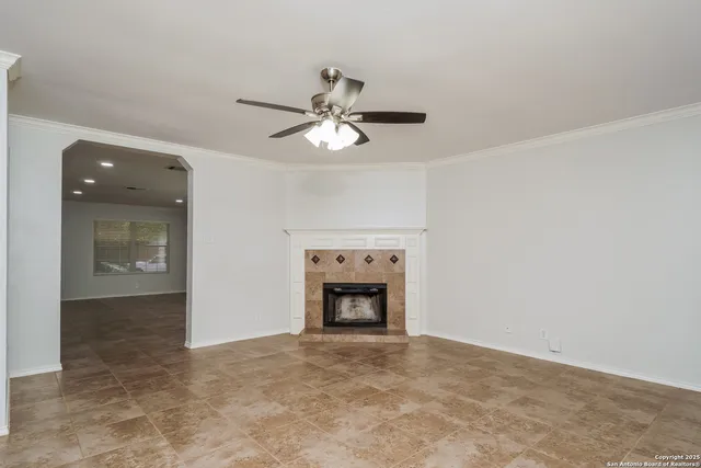 a view of an empty room with a fireplace and a chandelier fan
