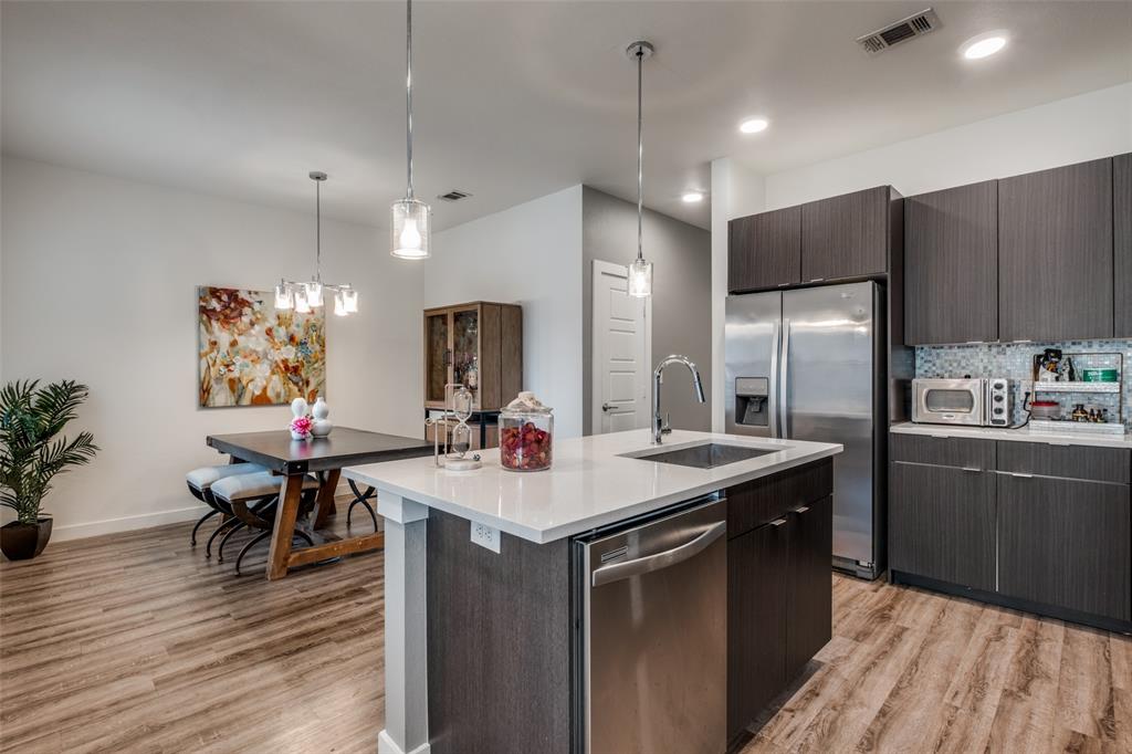 349 Tonga Street Dallas, TX 75203 - Photo 19 of 40 a kitchen with stainless steel appliances granite countertop a refrigerator a sink dishwasher a dining table and chairs with wooden floor