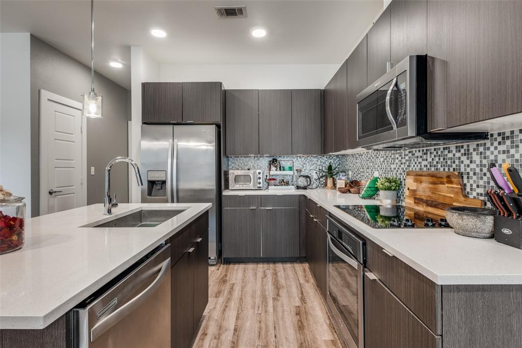 349 Tonga Street Dallas, TX 75203 - Photo 21 of 40 a kitchen with stainless steel appliances a sink dishwasher a refrigerator a microwave oven with cabinets and wooden floor