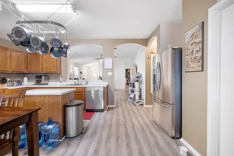 a kitchen with stainless steel appliances granite countertop a stove top oven a sink a dining table and chairs with wooden floor