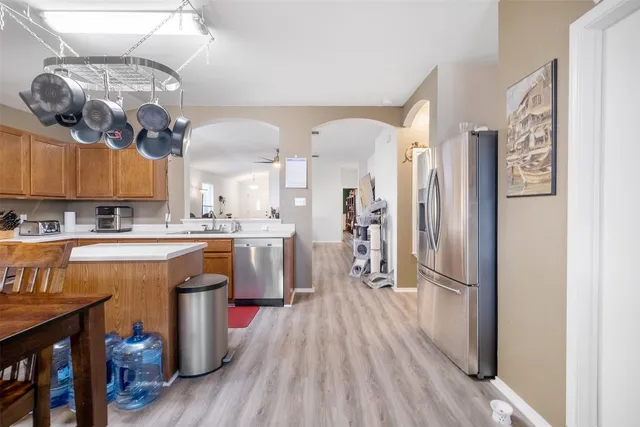 a kitchen with stainless steel appliances granite countertop a stove top oven a sink a dining table and chairs with wooden floor