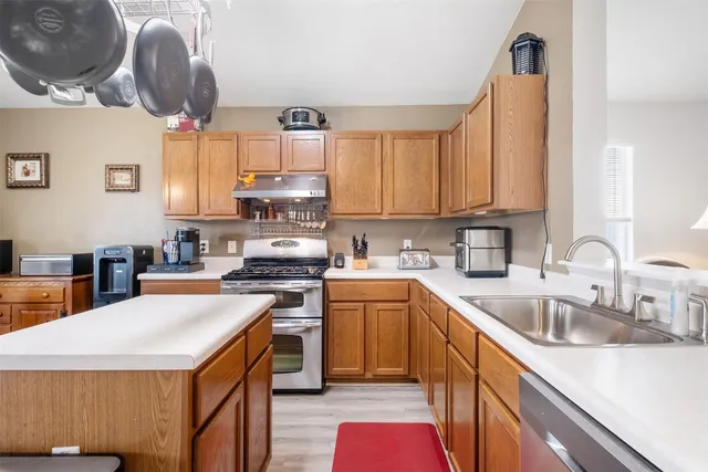 a kitchen with stainless steel appliances a stove a sink a chimney a dining table and chairs