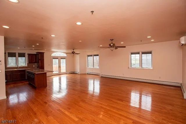 a view of empty room with wooden floor and kitchen