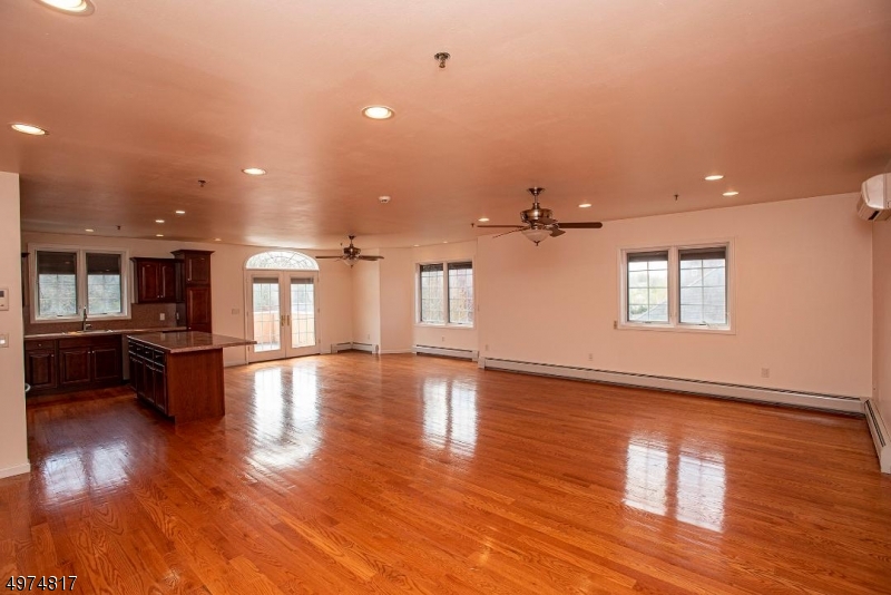 a view of empty room with wooden floor and kitchen