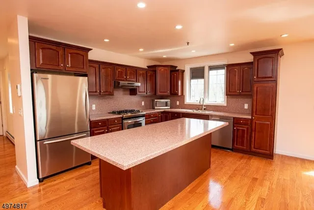 a kitchen with stainless steel appliances granite countertop a refrigerator a sink and a stove