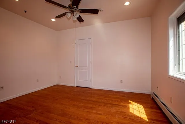 a view of empty room with wooden floor and fan