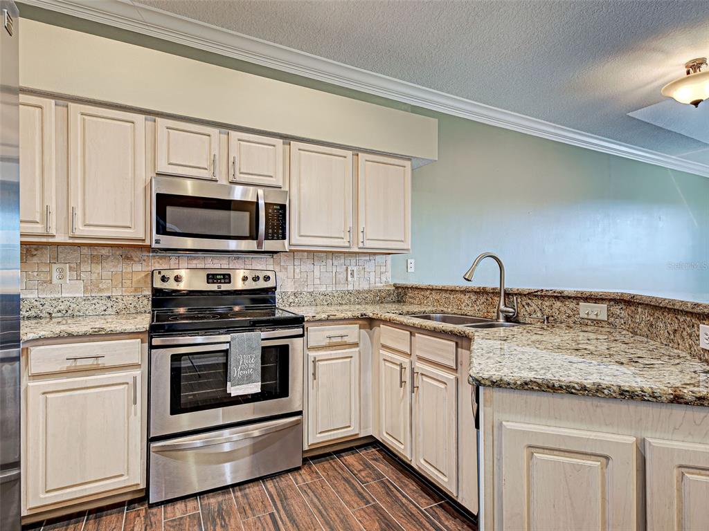 1801 Highland Road Osprey, FL 34229 - Photo 12 of 40 a kitchen with stainless steel appliances granite countertop a stove top oven a sink and white cabinets