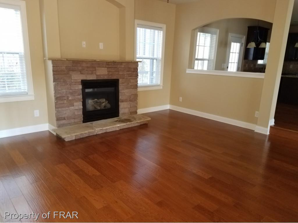355 Regimental Drive Cameron, NC 28326 - Photo 4 of 19 an empty room with wooden floor fireplace and windows